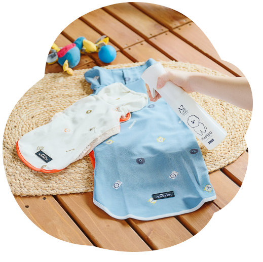 カーペットに並べたペット用衣服にマイクロミストスプレーを吹きかけている写真